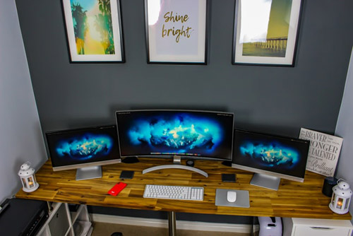 Three flat screen monitors on the desk