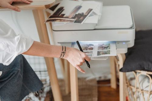 Woman printing photos on paper while working at home