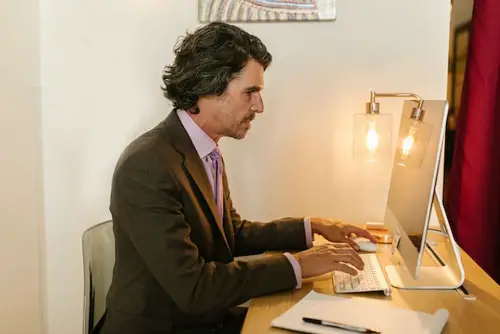 A Man in Gray Suit working on a Mac computer