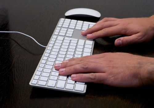 Man Using Arrow Keys and Letters Keys on a White Keyboard