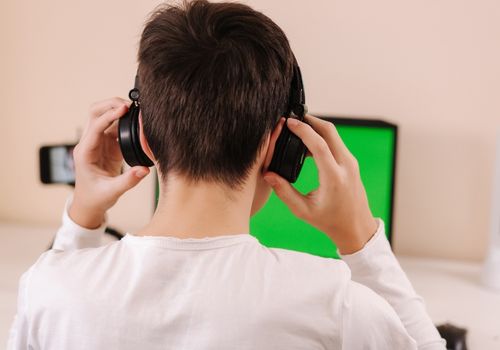 Young Boy Using Headphones and Laptop on Table