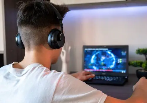 Young Boy with Headset Playing a Game on His Laptop