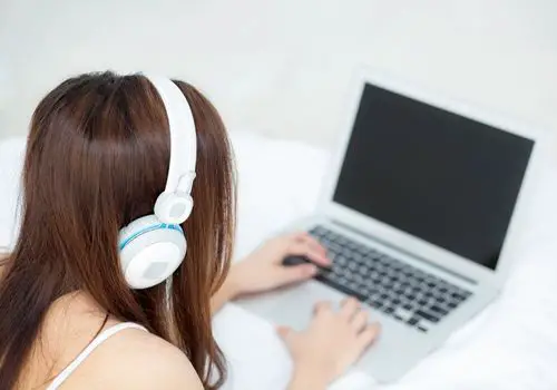 Young Woman with Headsets Working on Laptop