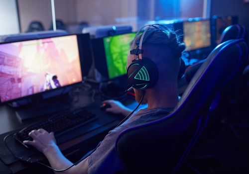 A Man Wearing Black Headphones Playing a Computer Game