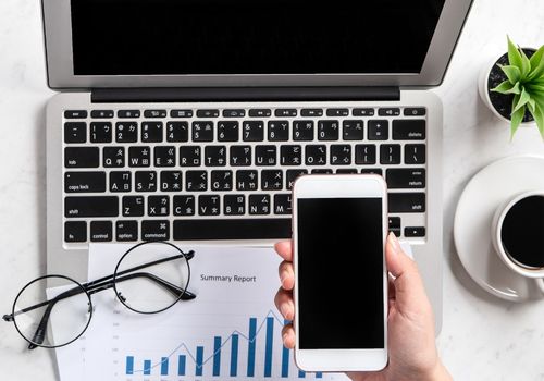 Laptop and Eye Glasses along with a mobile phone on person's hand