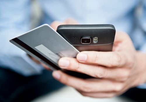 Man Using Smartphone with Debit Card For Online Banking