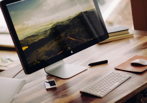 Space Grey iMac Near Magic Keyboard on a Wooden Desk