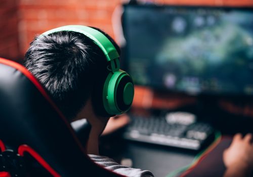 Kid with a Green Headset Playing a Computer Game