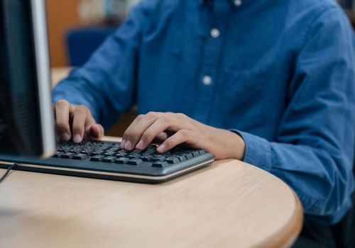 Man with Blue Shirt Types on a Keyboard