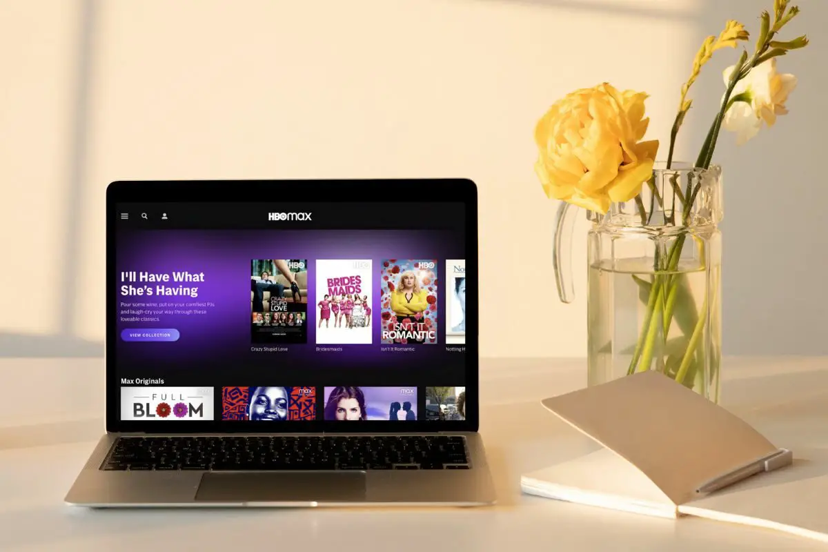 HBO Max Interface on Laptop beside a Notebook and Flower Vase