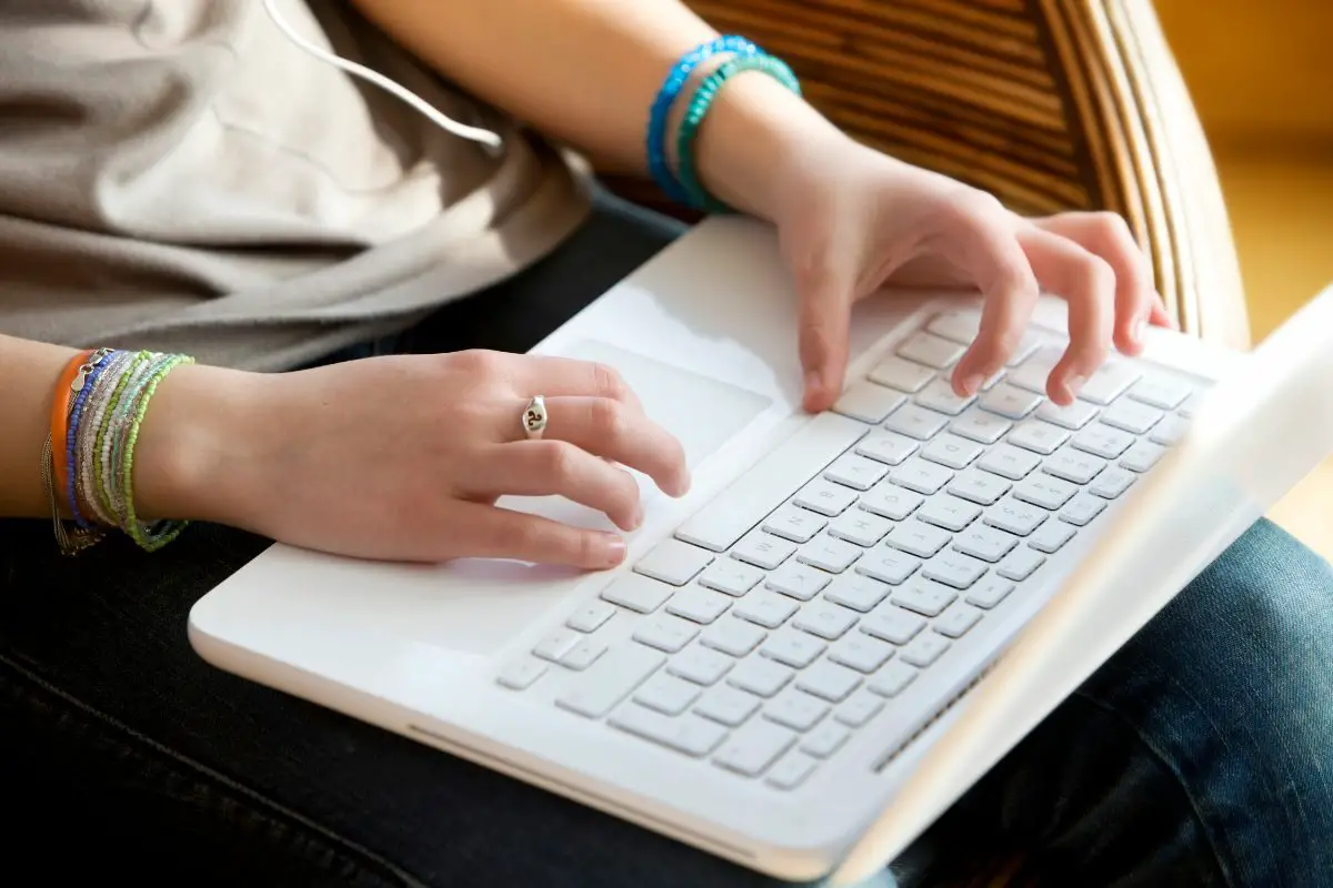 Teen Girl Typing on the White Laptop