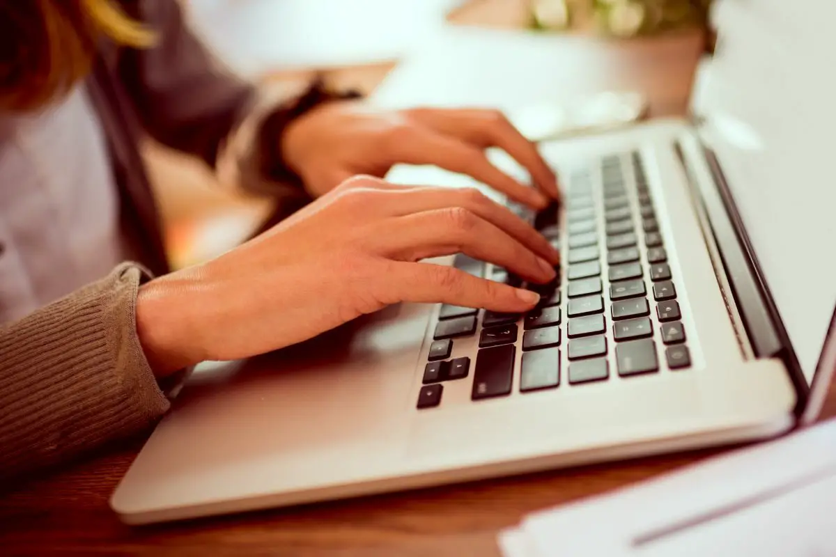 Female Office Worker Typing Using the Laptop