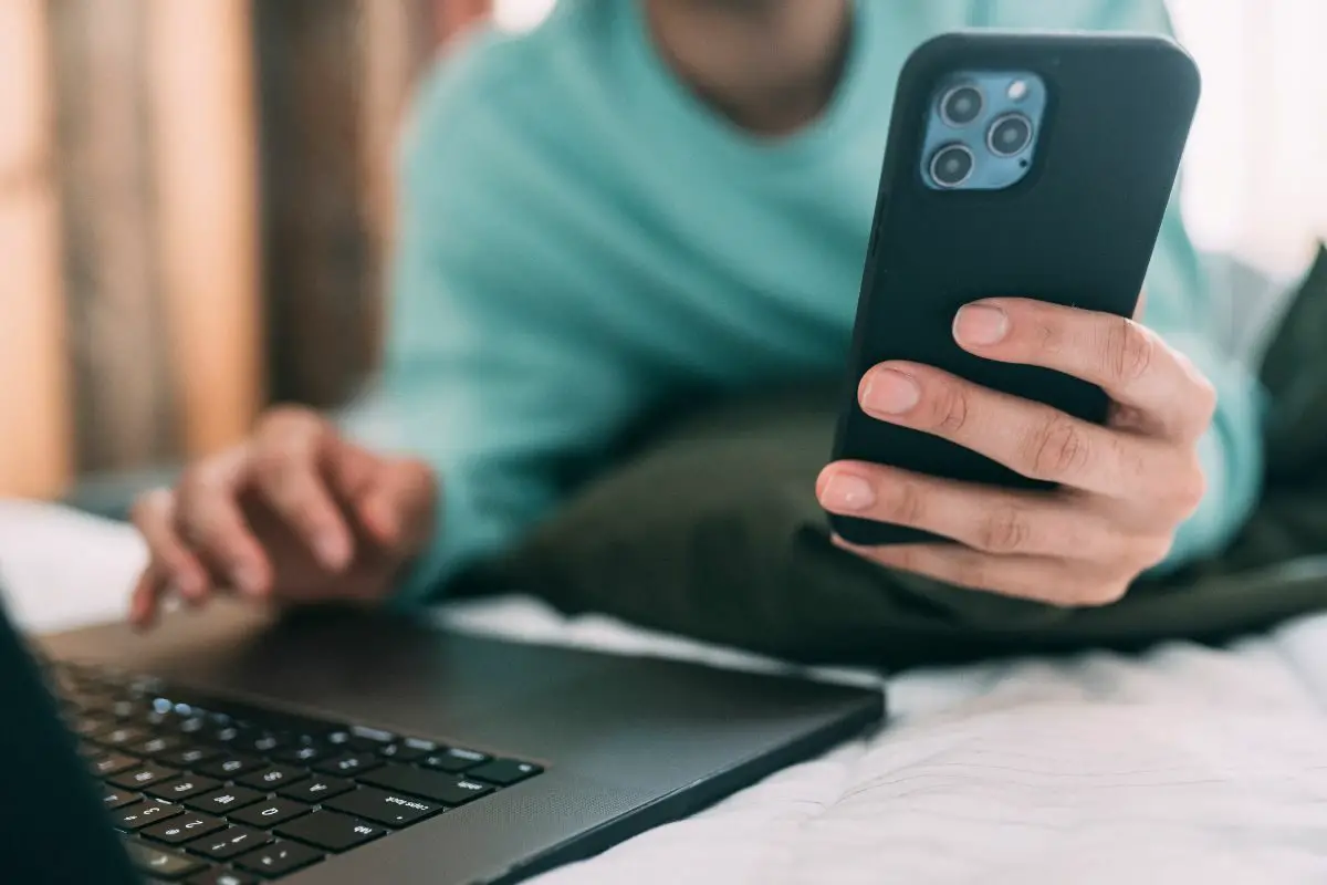 Man with a Laptop Browsing on Smartphone