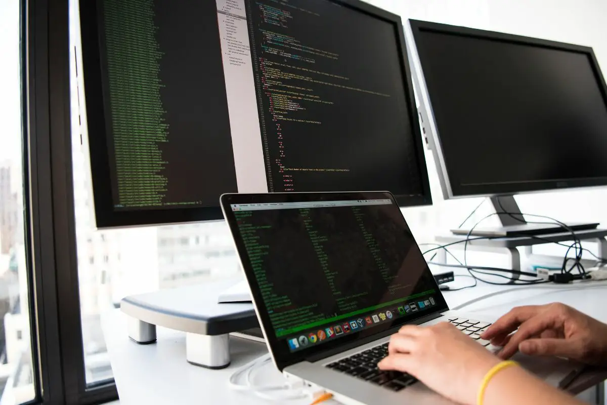 Person Working on Laptop with Multiple Screens