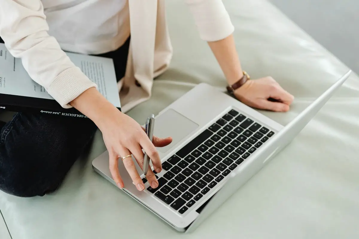 Woman Holding a Pen and Using the Laptop