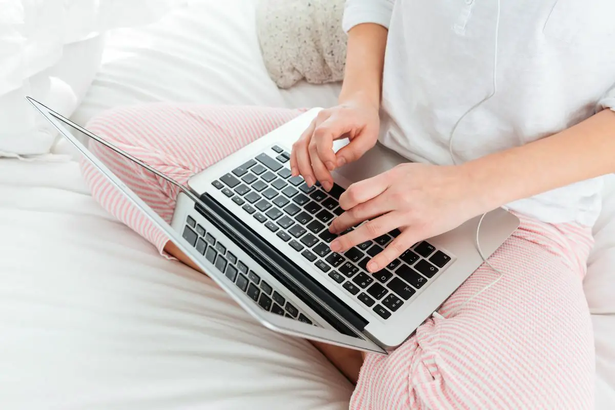 Woman Using Laptop Sitting on the Comfy Bed