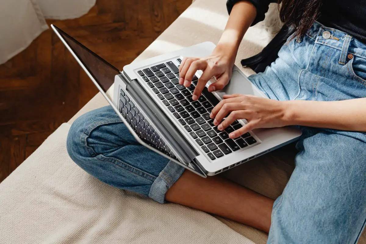 Young Woman Sitting on the Bed and Chatting Using Laptop