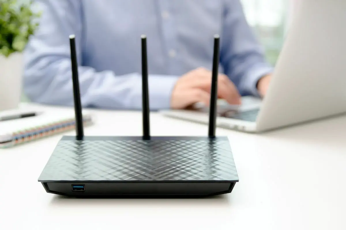 Man Working on a Laptop Beside a Wifi Router