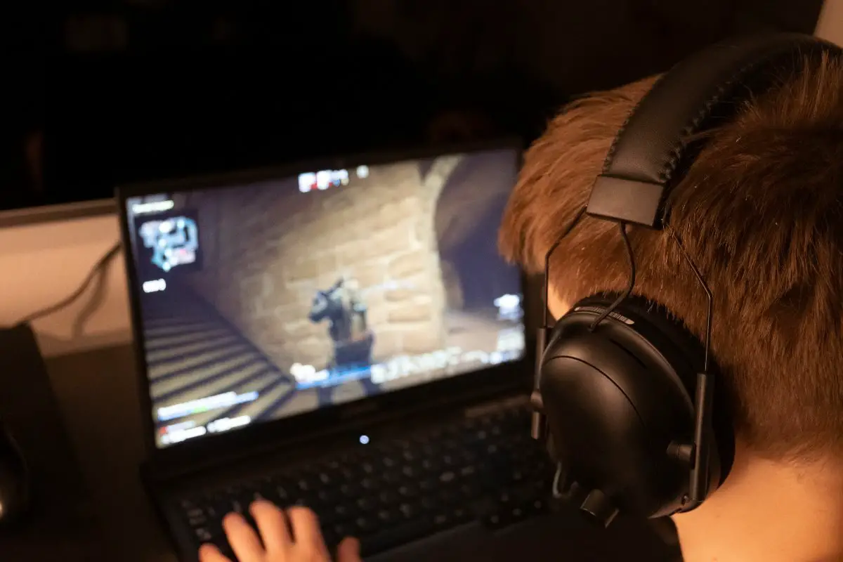 Player with Black Headphones Playing Live Game on Laptop