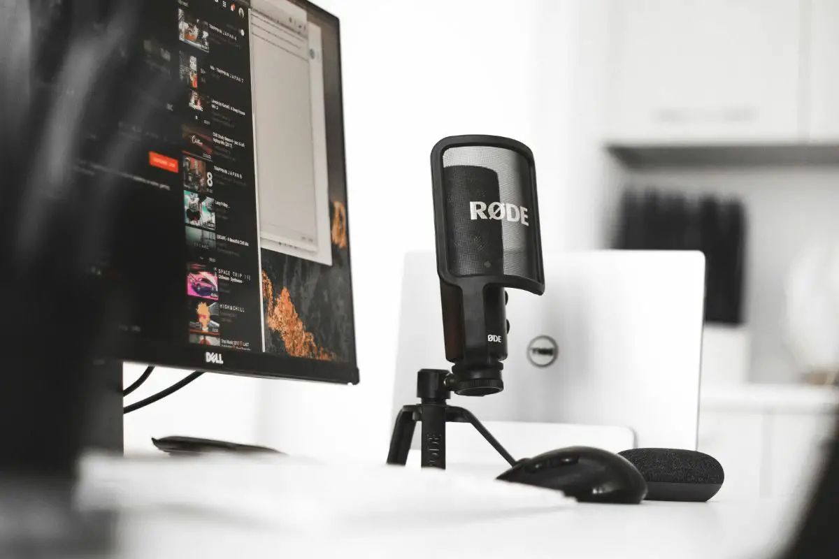 Black Rode Condenser Microphone Beside Computer Monitor